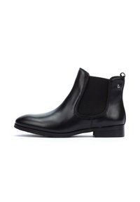 Bota Chelsea de cuero negro con paneles laterales elásticos, punta redonda, suela plana, mínima costura y un pequeño acento metálico en el tacón.