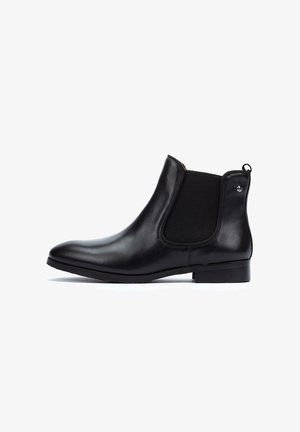 Black leather Chelsea boot with elastic side panels, round toe, flat sole, minimal stitching, and a small metal accent on the heel.