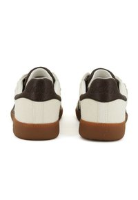 Pair of white low-top sneakers with brown leather heel tabs and gum rubber soles, viewed from the back on a white background.