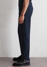 Navyblauwe broeken met een slim fit, gemaakt van lichtgewicht materiaal. Voorzien van een knoop op de achterzak en een schone, rechte pijpdesign.
