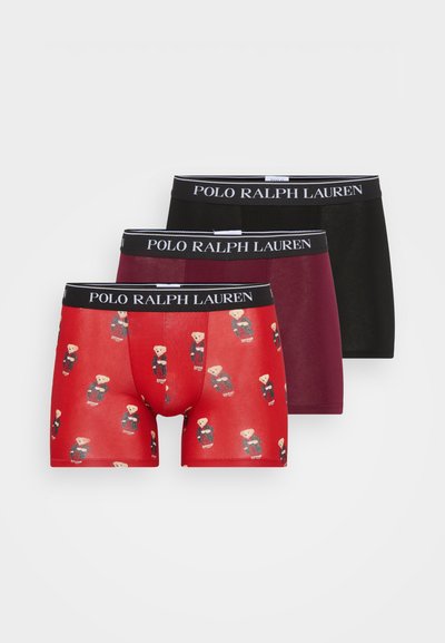 Trīs boxer šortos pāri: sarkani ar lāča rakstu, bordo un melni. Visām ir tumši melna jostasvieta ar "POLO RALPH LAUREN" logotipu.