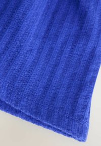 Tessuto blu con righe e una texture morbida. Il bordo presenta un orlo pulito che mette in evidenza il suo motivo tessuto e la finitura liscia.