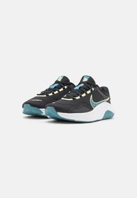 Sorte atletik sko med mesh-øvre, turkis accenter, limegrønne snørebånd og hvid sål. Har en fremtrædende logo på siden.