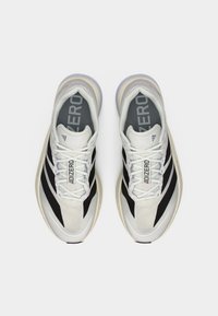 Weiße und schwarze Sportschuhe mit Mesh-Obermaterial, strukturierten Mustern und Gummisohlen. Versehen mit "ADIZERO"-Branding auf den Einlegesohlen.