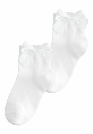 Paar weiße Knöchelsocken mit Spitzenbesatz und dekorativen Schleifen an den Bündchen, aus geripptem Stoff gefertigt.