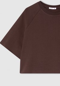 T-shirt marrone a maniche corte realizzato in cotone morbido con una vestibilità rilassata, caratterizzato da un collo a giro e maniche raglan.