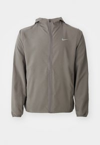 Sweat à capuche gris à zip intégral avec poignets élastiques et petit logo Nike sur la poitrine gauche, présenté sur un fond blanc.