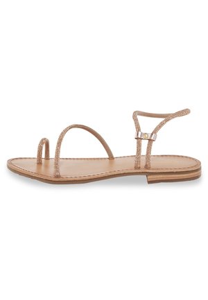 Flad sandal med en beige lædersål, to perlestraps og et minimalistisk design. Har et smalt ankelrem og små dekorative hardware.