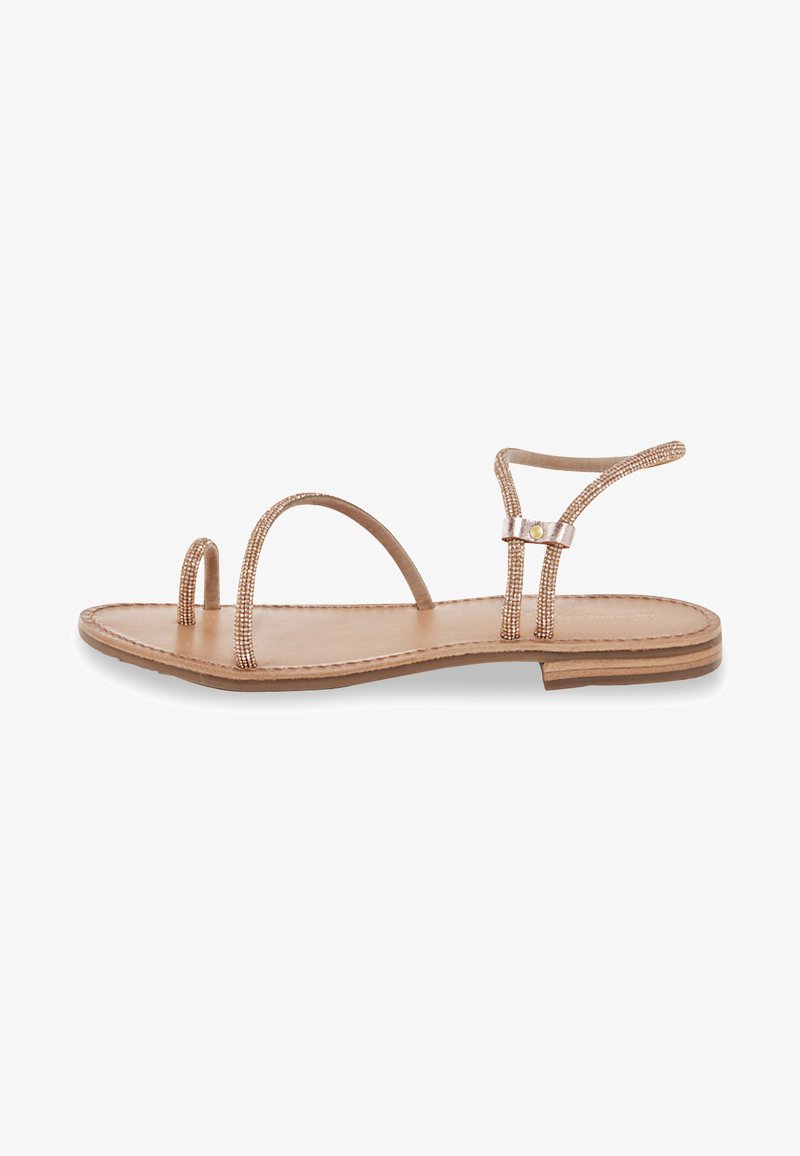 Flat sandal with a beige leather sole, two beaded straps, and a minimalistic design. Features a narrow ankle strap and small decorative hardware.