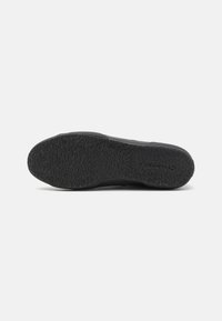 Black rubber shoe sole featuring a textured, patterned surface for grip, with smooth edges and no visible branding or logos.
