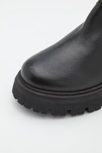 Bottine en cuir synthétique noir avec un bout arrondi, une tige texturée et une semelle épaisse et robuste avec des crampons profonds pour une meilleure adhérence.
