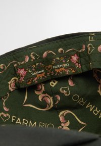 Green patterned fabric interior with floral and animal motifs, featuring tags for Barbour and FARM RIO, stitched along the edge.