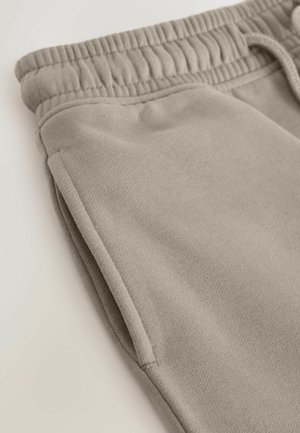 Helle beige Sweatpants aus weichem Stoff mit einem elastischen Bund und seitlichen Taschen. Die Textur ist glatt und sie haben eine lockere Passform.