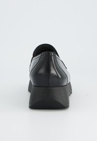 Black patent leather shoe with a rounded back, textured surface, and a low, sturdy rubber sole. Features a subtle logo on the heel.