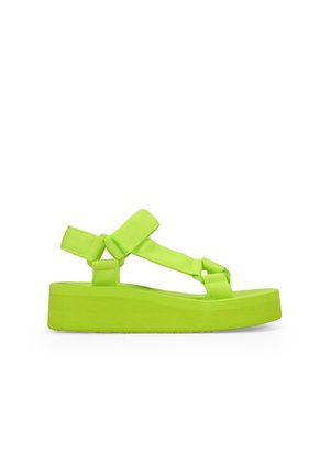 Sandalias de plataforma verde neón con suela de goma texturizada, correas ajustables y un diseño minimalista. Elevación proporcionada por la suela gruesa.