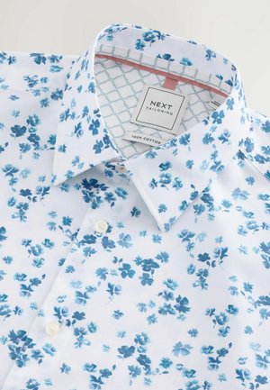 Weißes Baumwollhemd mit blauem Blumenmuster, klassischem Kragen und einem Markenetikett am inneren Hals mit gemusterten Akzenten.