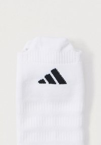 Biała sportowa skarpetka z teksturowanym prążkowaniem, z czarnym logo Adidasa po bokach oraz wzmocnionym palcem.