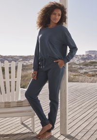 Dunkelblaues, strukturiertes Loungewear-Set mit einem lockeren Langarmtop und tapered Hosen mit verstellbarem Kordelzugbund und Taschen.