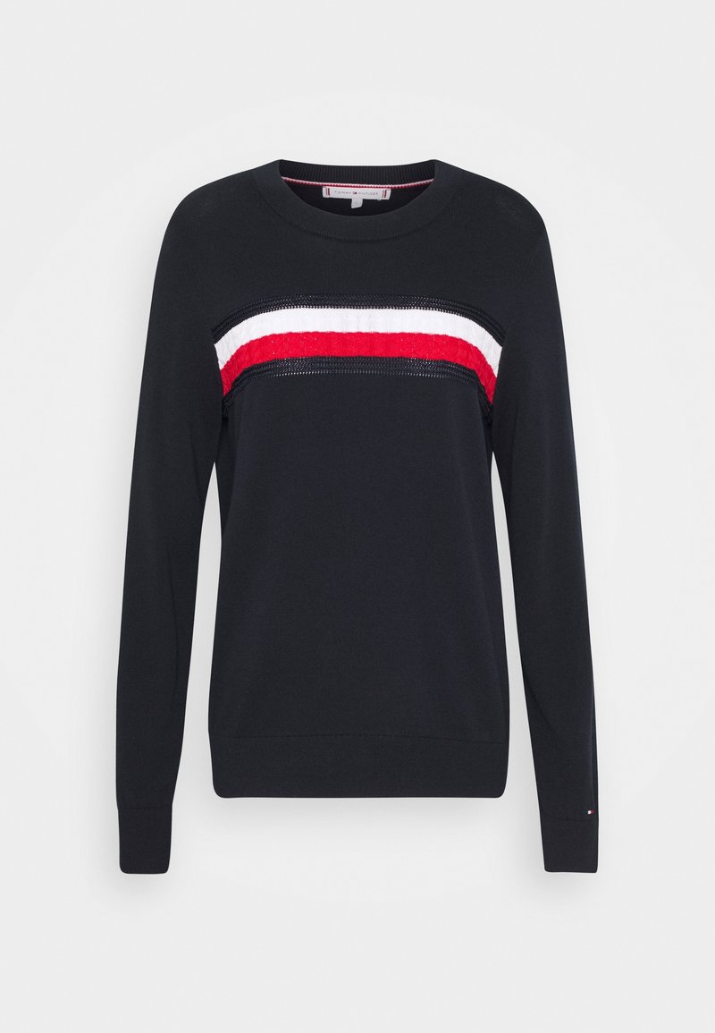 Pull bleu marine présentant un motif à rayures horizontales rouges, blanches et noires sur la poitrine, avec des poignets et un col côtelés.