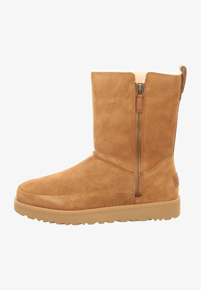 Botte d'hiver en daim couleur fauve de hauteur moyenne avec fermeture éclair latérale et semelle épaisse, dotée d'une doublure intérieure douce visible sur le bord supérieur.