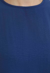 Navy blue fabric with a smooth texture and slight sheen, featuring a round neckline and minimal wrinkles.