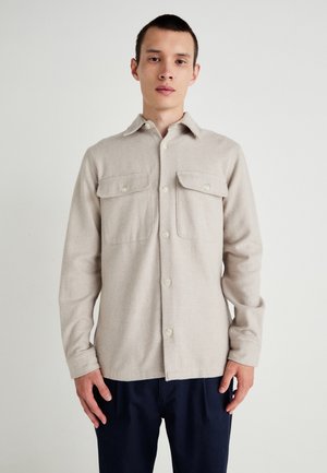 Beige flanellen overhemd met een puntige kraag, twee borstzakken en sluiting met knopen aan de voorkant, met een zachte textuur en lange mouwen.