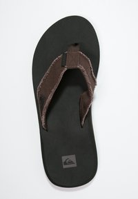 Barna gumilapú flip-flop, texturált talpbéléssel. Szövetpántokkal rendelkezik, bolyhos béléssel, és logó található a talp sarkában.