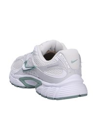 Sneaker atletica bianca con tomaia in rete, colletto imbottito e accenti turchesi. Presenta una suola testurizzata e dettagli di branding sulla parte posteriore e laterale.