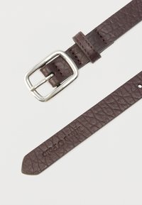 Brązowy skórzany pasek z fakturowaną powierzchnią, wyposażony w srebrną metalową klamrę i przeszywaną pętlę. Koniec paska jest zwężany z zaokrąglonymi krawędziami.