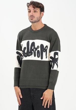 Maglione a maglia verde oliva con colletto a girocollo a coste, caratterizzato da audaci testi in stile graffiti neri e due righe orizzontali bianche.