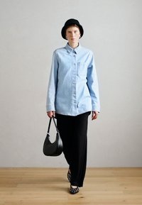 Ανοιχτό μπλε τζιν πουκάμισο, με μακριά μανίκια, κουμπωτή μπροστινή πλευρά, μία τσέπη στο στήθος. Μαύρο παντελόνι σε φαρδιά γραμμή και μαύρη τσάντα χειρός. Μαύρο καπέλο και παπούτσια με λευκές λεπτομέρειες.