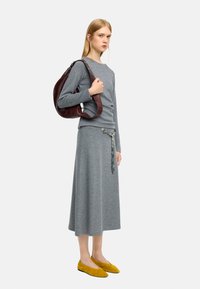 Szary długi rękaw bluzka i dopasowana spódnica z bocznym rozcięciem, zestawiona z żółtymi zamszowymi balerinkami. Ciemnoczerwona skórzana torebka na ramię dopełnia outfit.