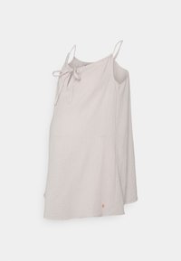 Light beige maternity top made of textured fabric. Features adjustable straps, a tie at the neckline, and a logo detail near the hem.