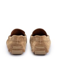 Mocassini in suede beige con profilo basso, retro arrotondato e suola in gomma a contrasto; presenta il logo del marchio impresso sul tallone.
