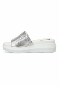 Zilveren metalen slide-on sandalen met een brede band, witte platformzool, gladde textuur en een minimalistisch ontwerp.