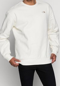 Vitt sweatshirt med rundad halsringning, ribbade ärmslut och nederkant. Har en liten logga på bröstet. Tillverkat av mjukt, strukturerat tyg.