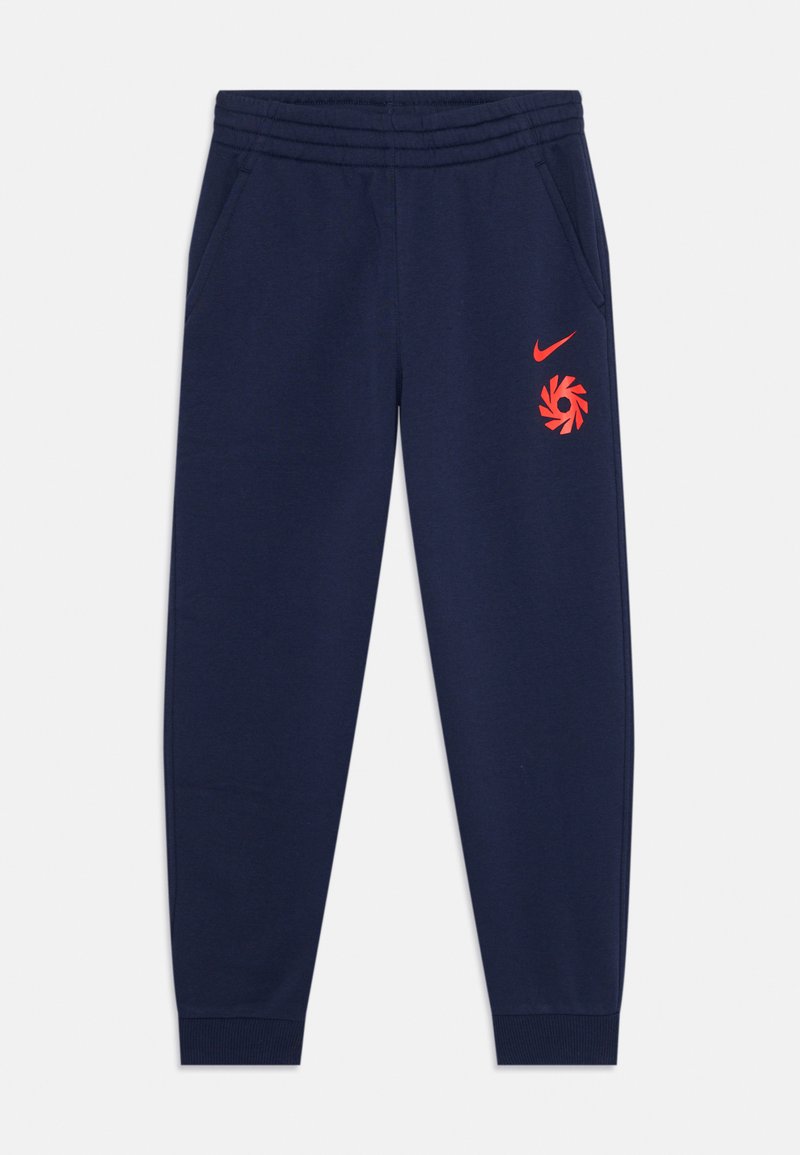 Tumši zili Nike sporta bikses ar sašaurinātu kāju, elastīgu jostu, sānu kabatām un sarkanu logo dizainu uz augšstilba.