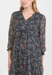 Kwiatowa sukienka z prześwitującego granatowego materiału z dekoltem w serek i marszczoną talią. Posiada wielokolorowe wzory kwiatowe oraz elastyczne rękawy.