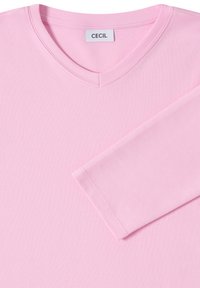 Chemise rose clair à manches longues avec un col en V, fabriquée en tissu doux, présentant des détails de couture le long de l'encolure et des bords des manches. Étiquette : CECIL.