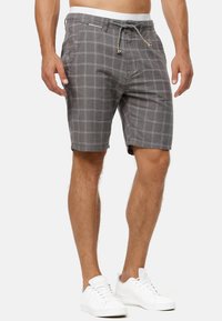 Shorts à carreaux gris en tissu mélangé coton. Comprend des poches latérales, une taille élastique avec cordon de serrage, et un motif de grille blanche contrastant.