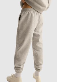 Szare dresy wykonane z miękkiego materiału, charakteryzujące się luźnym krojem, elastycznym pasem i zwężanymi mankietami. Posiadają boczne kieszenie dla większej funkcjonalności.