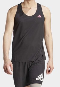 Czarny sportowy top na ramiączkach z siateczkową teksturą, z różowymi akcentami i małym logo. W połączeniu z czarnymi szortami z białym logo.