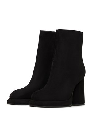 Botine negre din suede, cu o textură netedă, vârf rotund, toc înalt cub și închidere cu fermoar pe lateral. Talpa prezintă un contrast ușor.