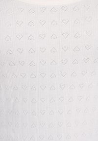 Tela blanca con un patrón de pequeños agujeros en forma de corazón, distribuidos uniformemente en filas horizontales y verticales.