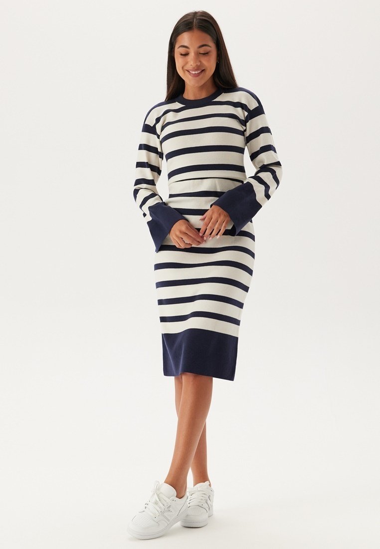 Gestreift gestricktes Kleid in Marineblau und Cremefarben, mit langen Ärmeln und breiten Bündchen, sowie einer figurbetonten Silhouette, die bis zum Knie reicht.