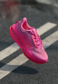 Rosa Sportschuh mit einem Mesh-Obermaterial, gepolstertem Kragen und sichtbarer Luftpolsterung in der Sohle. Mit einem Swoosh-Logo und strukturierten Details.