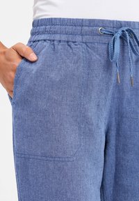 Blue lightweight joggers with an elastic waistband and drawstring, featuring side pockets and a soft, textured fabric.