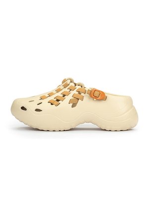 Chaussure style sabot beige clair avec une surface texturée, des trous d'aération découpés, un design à lacets et une sangle ajustable marron.