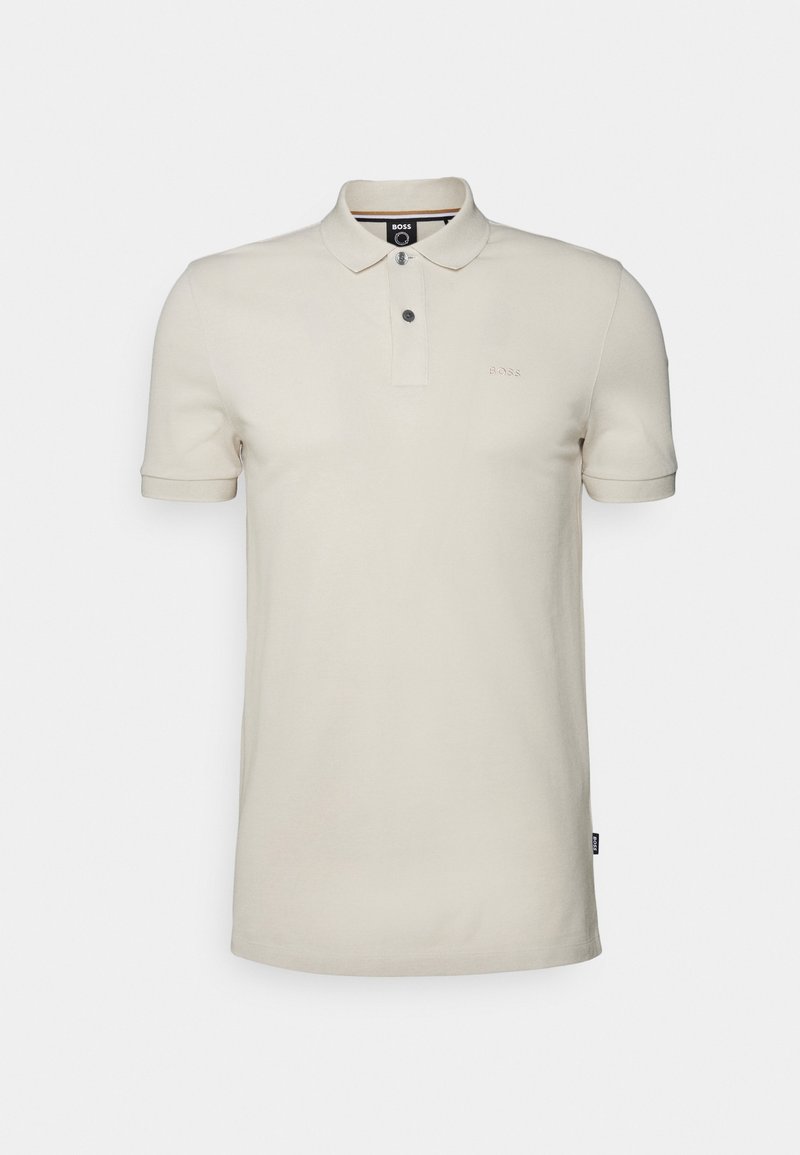 Polo manches courtes en coton beige clair, doté d'un col classique, d'une patte de boutonnage à trois boutons et d'un logo subtilement brodé sur la poitrine.