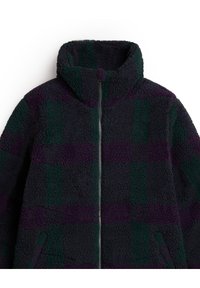 Fleecejacke mit hohem Kragen, Reißverschluss, kariertem Muster in Dunkelgrün und Lila, strukturiertem Äußeren und zwei Seitentaschen.